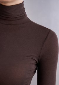 Brauner Rollkragenpullover mit figurbetontem Schnitt, aus glattem, dehnbarem Stoff gefertigt. Mit hohem Kragen und langen Ärmeln. Nahaufnahme.