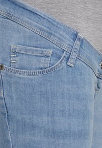 Jeans de ganga azul claro com um design clássico de cinco bolsos. Apresenta costuras visíveis, um pequeno bolso para moedas e uma textura levemente desgastada.