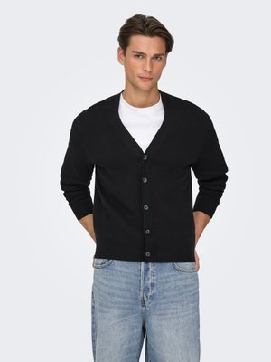 Black cardigan with a V-neck, front buttons, and long sleeves. Worn over a white t-shirt, paired with light blue jeans.