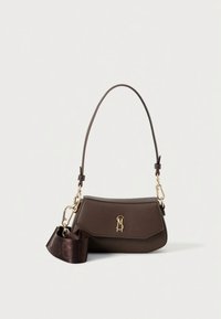 Brūna ādas soma ar izliekta forma, zelta metāla detaļām un noņemamu siksnu ar reljefu logotipu. Gluda tekstūra, minimālistisks dizains.