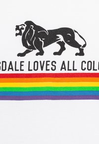 Hvid t-shirt med et sort løvegrafik og teksten "Lonsdale elsker alle farver" over et regnbue-stribet design.