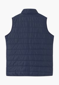 Granatowa pikowana kamizelka z stójką, z pionowym przeszyciem i gładką, lekko błyszczącą fakturą. Bez rękawów.