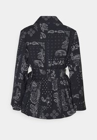 Černá bunda s páskem, ozdobená bílými vzory paisley a bandana, s dlouhými rukávy a špičatým límcem, zobrazená zezadu.