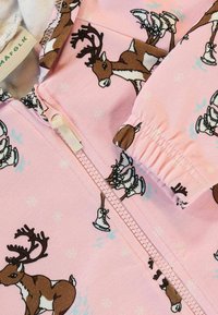 Roza zip-up kombinezon s uzorkom jelena i detaljima klizaljki, napravljen od mekanog materijala s elastičnim manžetama i udobnom podstavom.