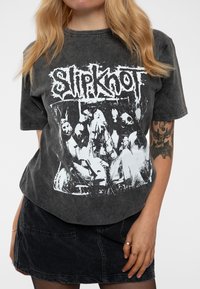 Dark gray cotton T-shirt featuring a large white Slipknot graphic with band imagery. Loose fit, round neck, short sleeves, and soft texture.