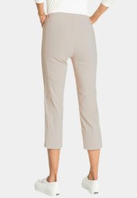 Lichtbeige, cropped broeken met een gladde textuur, voorzien van een getailleerd ontwerp en minimalistische achterzakken, gecombineerd met witte platform sneakers.