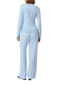 Hellblaues Sweater aus weichem Stoff, kombiniert mit passenden hellblauen Hosen. Lockere Passform, lange Ärmel und gerippte Bündchen am Sweater.