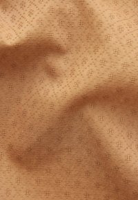 Svijetlosmeđi materijal s suptilnim dijamantnim uzorkom i izbočenom teksturom. Glatka površina s malim geometrijskim motivima kroz cijelu tkaninu.