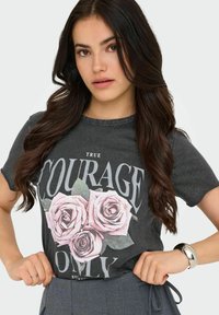 Camiseta de algodón gris con una impresión gráfica de tres rosas rosas y el texto en negrita que dice "SOLO VERDADERO VALOR". Manga corta, ajuste relajado.