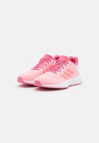 Zapatillas deportivas rosas con parte superior de malla, cuello acolchado y diseño de tres rayas. Suela intermedia blanca gruesa y suela exterior rosa con dibujo texturizado.