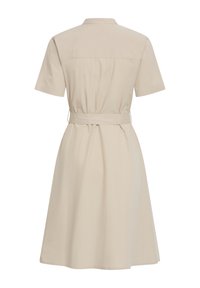 Beige jurk met korte mouwen, een kraag en een bijpassende riem die de taille benadrukt, gezien van achteren.