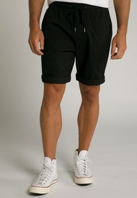 Sorte shorts med snor i taljen, opsmøgede manchetter og letvægtsstof; parret med hvide høj-top sneakers.