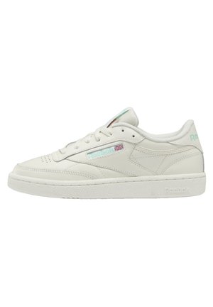 Sneaker blanc Reebok basse avec fermeture à lacets, semelle texturée et petit drapeau Union Jack sur la face latérale.