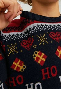 Sweter dzianinowy w granatowym kolorze, z wzorami czerwonych i żółtych serc, prezentów oraz płatków śniegu, a także z prążkowanym dekoltem.