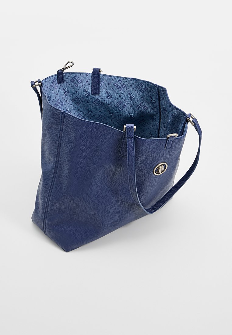 Bolso tote de piel azul marino con superficie texturizada, parte superior abierta y un interior de patrón contrastante. Cuenta con asas para el hombro y un acento de logo.