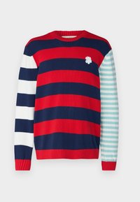 Pull-over en tricot à rayures horizontales rouges, bleu marine et blanches ; une manche présente des rayures turquoise et blanches. Accent floral sur la poitrine.