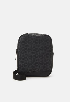 Bolso bandolera negro con un patrón de logotipo en relieve que se repite, forma rectangular elegante y un acabado mate contrastante en la base.