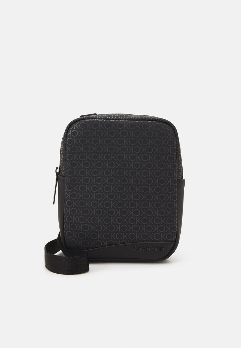 Bolso bandolera negro con un patrón de logotipo en relieve que se repite, forma rectangular elegante y un acabado mate contrastante en la base.
