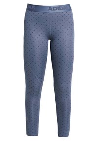 Niebieskie legginsy w czarne kropki, elastyczny materiał, zwężany krój nogawek oraz elastyczny pas z logo Adidas.