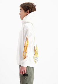 Witte hoodie met vlamgrafieken in oranje en geel op de mouwen. Heeft een relaxed fit en een zachte, textuurachtige stof.