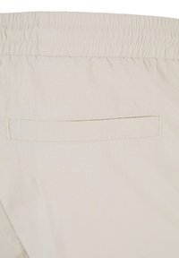 Lys beige shorts med elastisk midje, glatt tekstur og en enkelt baklomme med en sydd rektangulær åpning.