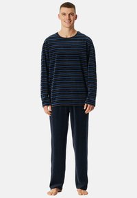 Camiseta de manga larga a rayas en tonos azul y negro, combinada con pantalones suaves en azul marino, hechos de un tejido de felpa.
