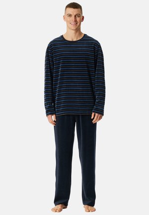 Maglietta a maniche lunghe con righe navy di varia tonalità blu e nera, abbinata a pantaloni navy morbidi, realizzati in tessuto peloso.