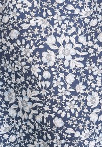 Tissu bleu avec un motif floral blanc comprenant diverses fleurs, feuilles et bourgeons disposés de manière dense avec un travail de lignes détaillé.