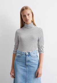 Musträiline musta ja valge turtleneck, keha järgi sobiv, pikkade varrukatega. Kombineeritud kõrge vöökohaga helesinise denim-seelikuga, millel on eesmine õmblus ja nööpkinni. 