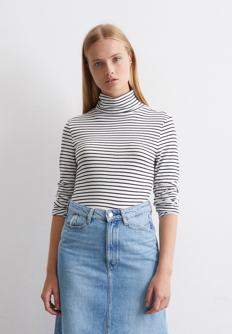 Svart og hvit stripete høyhalset genser, tettsittende, med lange ermer. Kombinert med et høyt liv lys blå denimskjørt, med søm foran og knappestolpe.