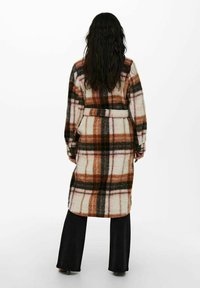 Longue robe à carreaux en tissu doux, présentant des tons de rose, marron et vert. Comprend une ceinture et des manches longues, avec une coupe confortable.