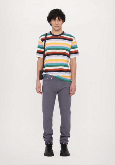 Rööbastega t-särk mitmevärviline (roheline, kollane, punane, sinine) lühikeste varrukatega, kombineeritud hallide slim-fit pükste ja mustade kingadega.