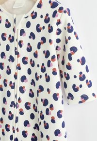 Hvidt stof med et farverigt leopardtryk i navy, pink og rust. Korte ærmer og rund halsudskæring med en lukning foran.