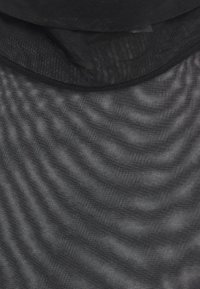 Gros plan sur un tissu en mesh noir transparent avec un fin filet et des plis doux créant des motifs subtils de vagues.
