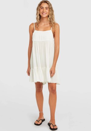 Valge varrukateta kleit reguleeritavate rihmadega, volangilise äärega, pehme tekstuuri ja voolava disainiga, põlveni ulatuv lõige. Sobitatud mustade sandaalidega.