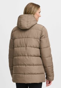 Doudoune marron avec capuche, dotée de sections matelassées, d'une texture lisse et d'une silhouette légèrement ajustée en bas.