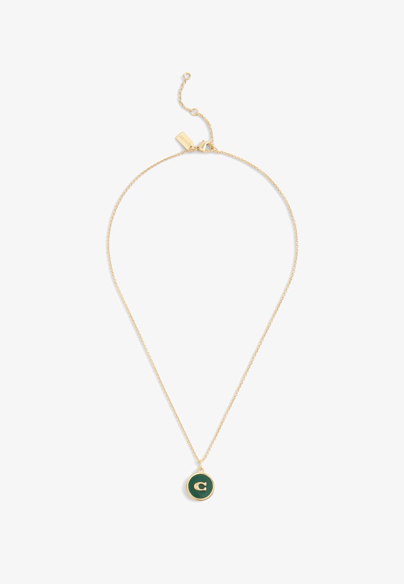 Guldkedja med en cirkulär hängsmycke som har en mörkgrön bakgrund och ett guld-bokstav "C" i mitten.