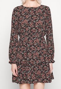 Vestido floral negro con mangas largas, que presenta un escote redondeado, cintura fruncida y un dobladillo acampanado. Acabados en flores rosas y blancas por todo el diseño.