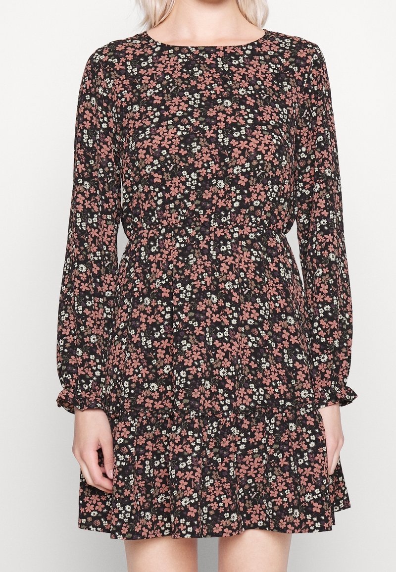 Vestido floral negro con mangas largas, que presenta un escote redondeado, cintura fruncida y un dobladillo acampanado. Acabados en flores rosas y blancas por todo el diseño.