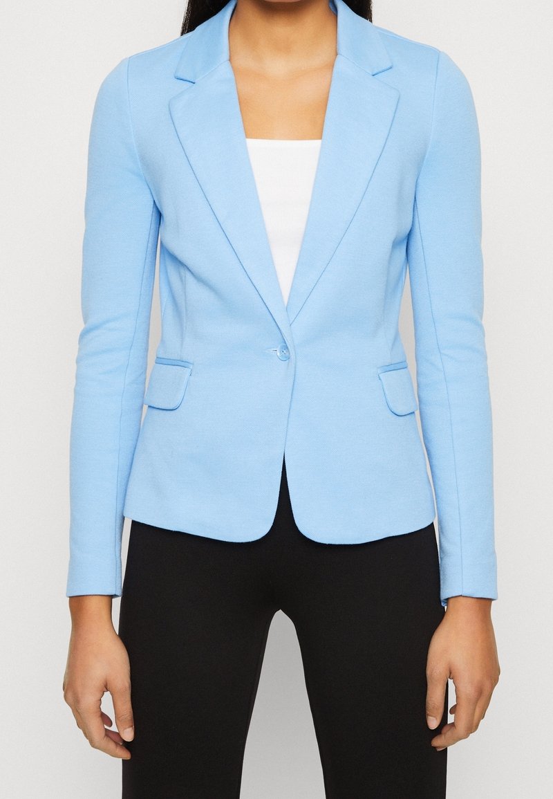 Jasnoniebieska marynarka z wyciętym kołnierzem, pojedynczym zapięciem na guzik i dwoma kieszeniami z przodu, wykonana z gładkiej, elastycznej tkaniny.