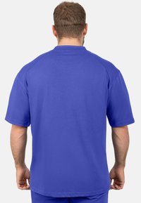 T-shirt violet à manches courtes en tissu lisse avec col rond, présentant une coupe décontractée et un design simple sans coutures à l'arrière.