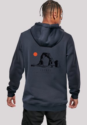Dark navy hoodie with a drawstring hood, featuring a graphic of a rock arch and a red sun on the back. Ribbed cuffs and hem.