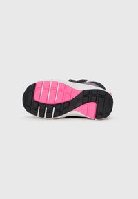 Semelle de chaussure de sport noire et rose dotée d'un design en caoutchouc texturé, avec des rainures profondes pour l'adhérence et un talon renforcé.