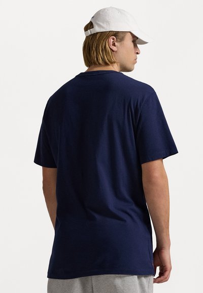 Tumši zils kokvilnas T-krekls ar īsām piedurknēm, parastā piegriezumā un ar apaļu kakla izgriezumu. Aizpuses virsma ir gluda, bez redzamām grafikām.