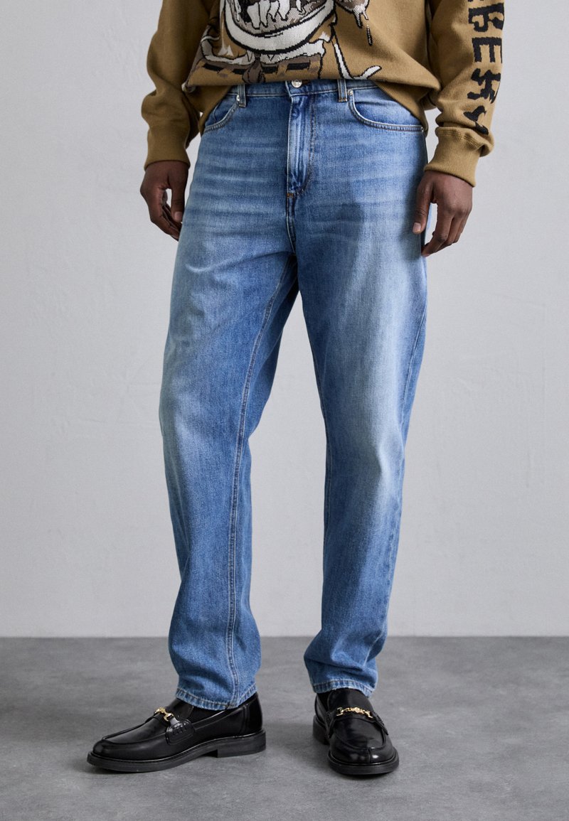 Lyseblå denimjeans med lige ben, der har en falmet vask og klassisk fem-lomme design, parret med sorte loafers.