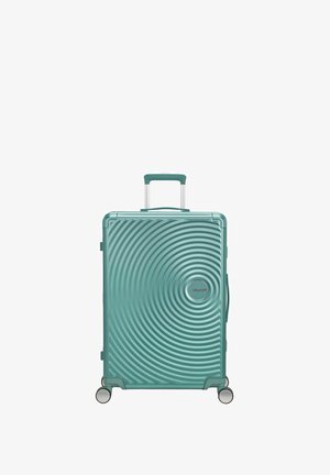 Valise rigide de couleur turquoise avec un motif en spirale, quatre roues, poignée rétractable et poignée latérale, posée verticalement sur fond blanc.