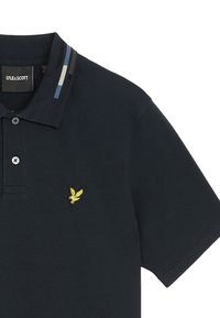 Polo shirt di un blu navy scuro in cotone, con un logo ricamato di un'aquila gialla sul petto e un colletto a righe blu, grigio e nero.