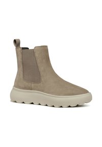 Bottes Chelsea en suede beige avec un panneau latéral élastique beige et une languette de tirage, dotées d'une semelle en caoutchouc blanc épais et texturé.