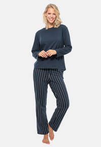Marinblå långärmad topp som matchas med marinblå randiga pyjamasbyxor. Mjuk tyg med en avslappnad passform. Byxorna har vita vertikala ränder och sidosprund.