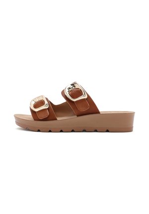Bruine leren slidesandalen met twee grote zilveren gespen, een platformzool en een gestructureerde buitenzool voor grip.